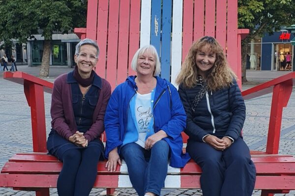 Heike, Ilme und Anne, Lehrkräfte der sozialpädagogischen Abteilung, sitzen auf einer großen Bank in Norwegen