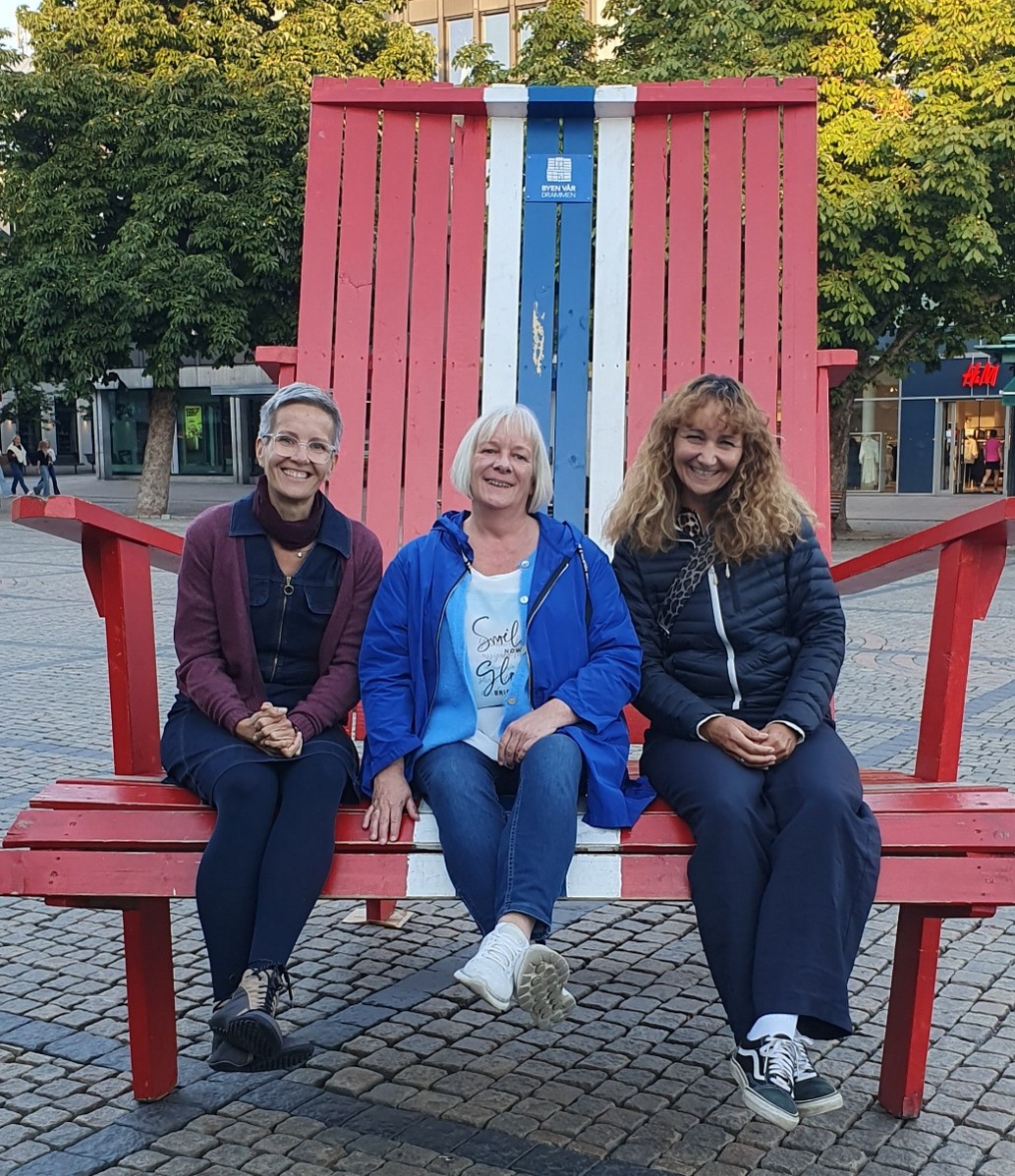 Heike, Ilme und Anne, Lehrkräfte der sozialpädagogischen Abteilung, sitzen auf einer großen Bank in Norwegen